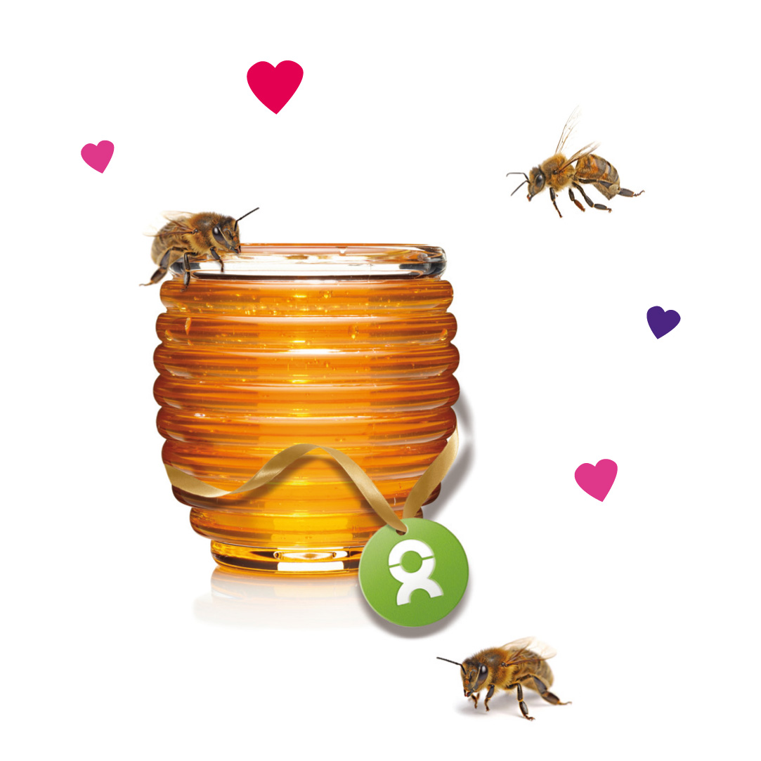 Beispiel Geschenk Spende Liebe zeigen Honigbienen fliegen um ein mit bunten Herzen umrahmtes Honigglas herum